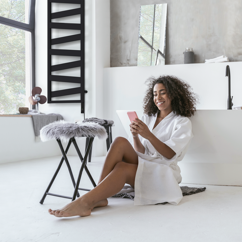 Frau im Badezimmer mit Zehnder Design Heizkörper