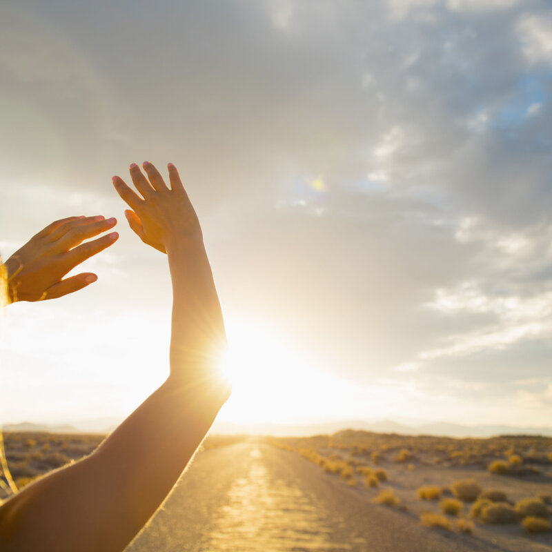 Hispanic woman shielding eyes from sun on remote road